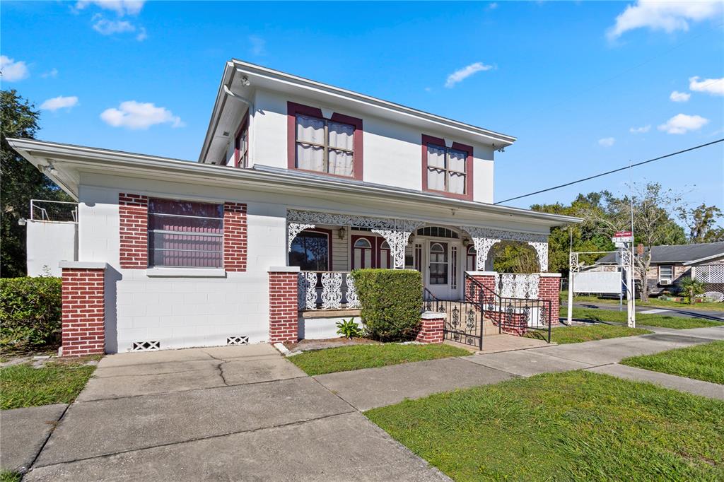 A two-story white house with brick accents and a front porch sits on a lawn — 900 S LOCUST AVENUE, SANFORD, FL