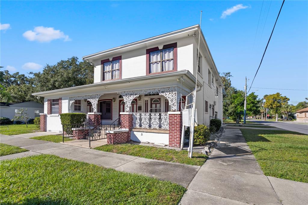 A two-story white house with a brick-based porch and ornate white metal railings — 900 S LOCUST AVENUE, SANFORD, FL