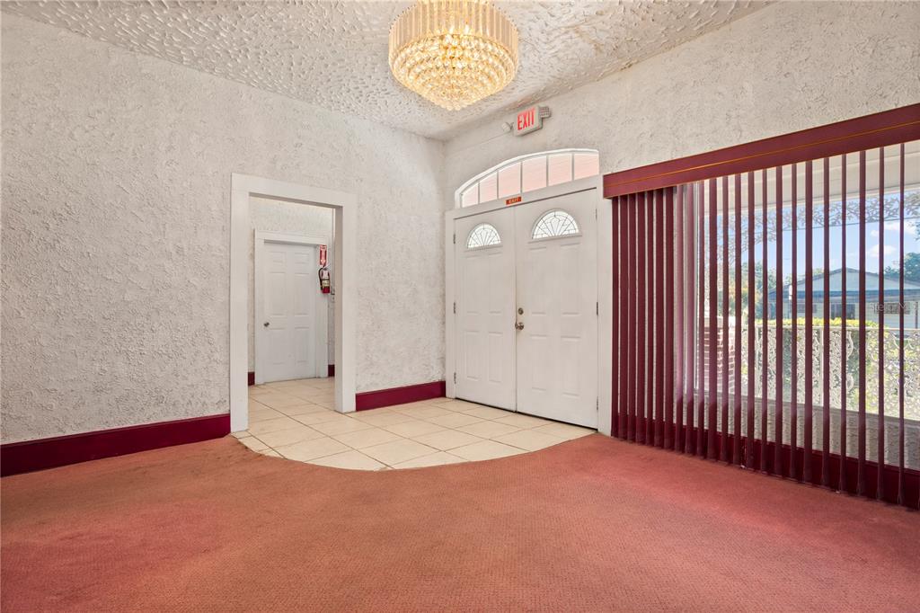 An interior entryway features a chandelier, red carpeting, tile flooring, and double front doors — 900 S LOCUST AVENUE, SANFORD, FL