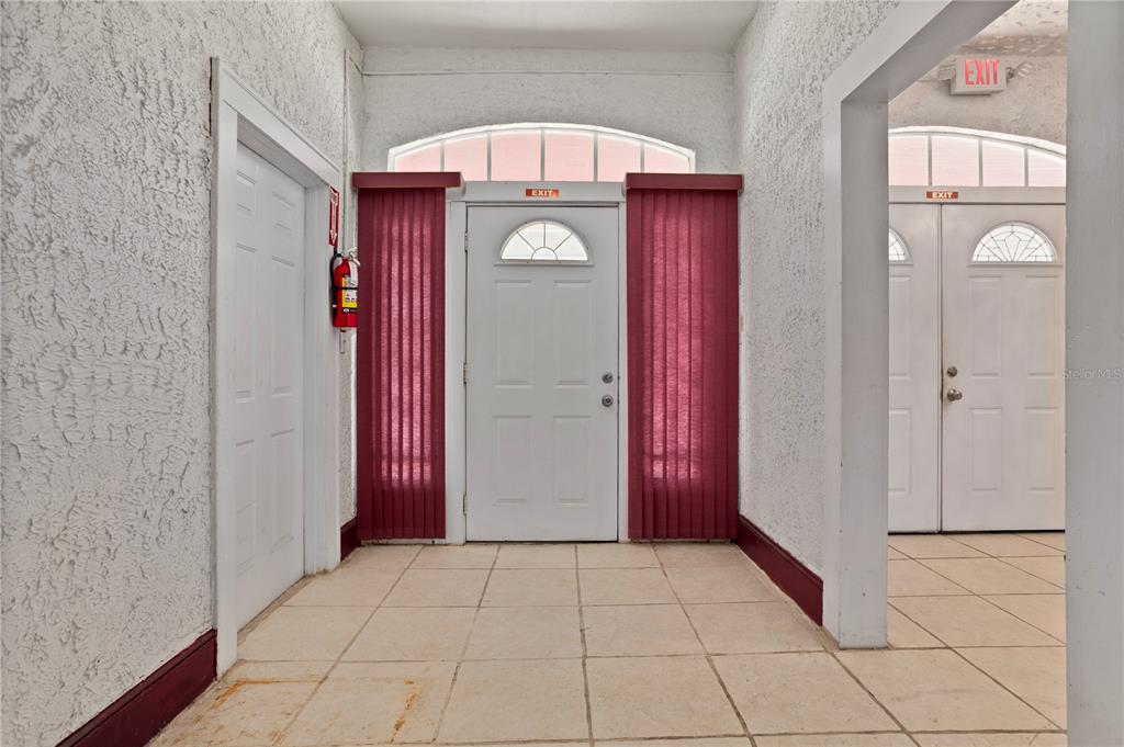 A tiled hallway features white walls, two white doors with arched windows, and exit signs — 900 S LOCUST AVENUE, SANFORD, FL