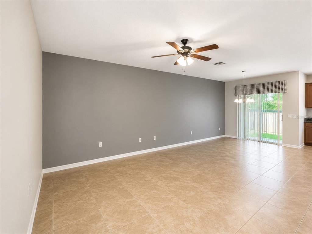 An empty living room features a large gray accent wall, tile flooring, and a ceiling fan — 5602 RUTHERFORD PLACE, OVIEDO, FL
