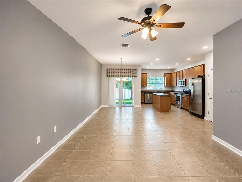 An open-concept kitchen and dining area features tile flooring, wood cabinets, and a ceiling fan — 5602 RUTHERFORD PLACE, OVIEDO, FL