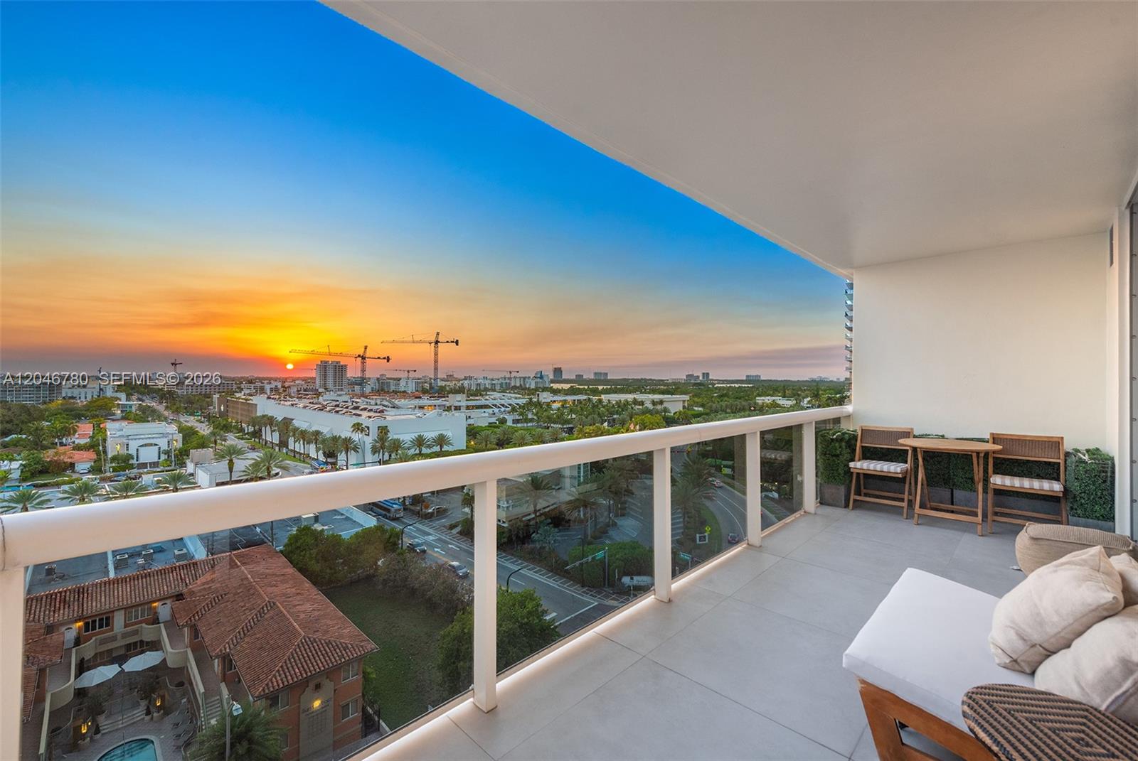 A balcony with a glass railing overlooks a city skyline at sunset — 9595 Collins Ave, Surfside FL 33154, SURFSIDE, FL