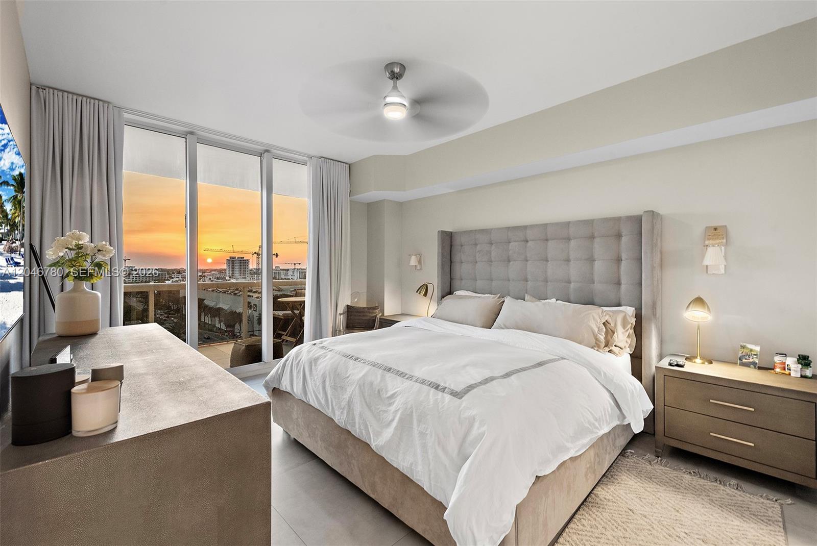 A bedroom features a tufted headboard, a ceiling fan, and floor-to-ceiling windows overlooking a sunset — 9595 Collins Ave, Surfside FL 33154, SURFSIDE, FL