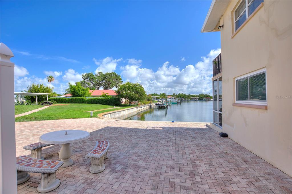 A paved patio overlooks a canal with a boat dock and a grassy lawn — 3753 46TH AVENUE S UNIT 10, ST PETERSBURG, FL