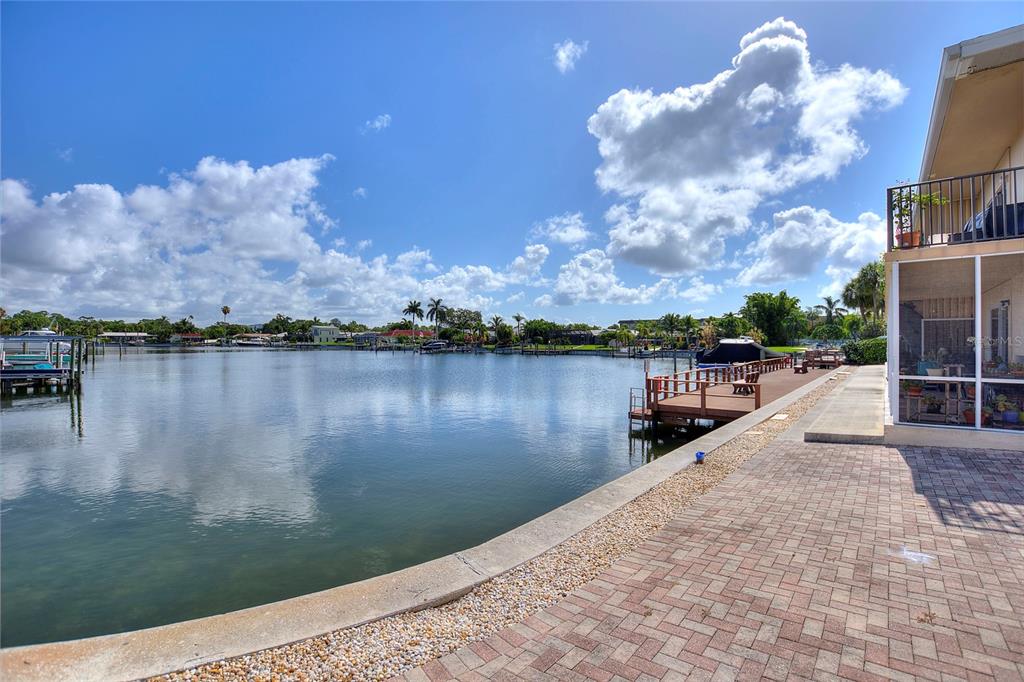 A paved patio overlooks a canal with a wooden dock and a screened-in porch — 3753 46TH AVENUE S UNIT 10, ST PETERSBURG, FL