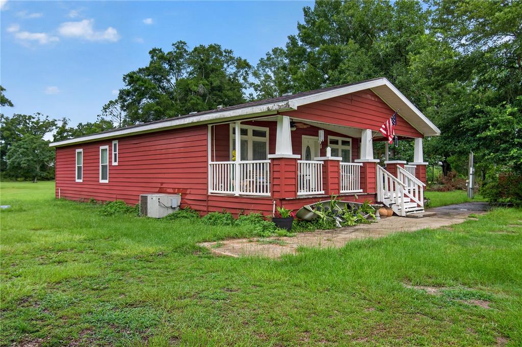 A red, single-story house with a covered front porch and white railings sits on grass — 17860 NW 73RD TERRACE, TRENTON, FL