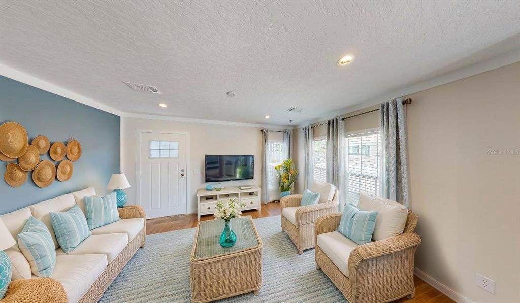 A living room features wicker furniture, a blue accent wall with wall baskets, and light flooring — 1556 BLUE HERON DRIVE, ENGLEWOOD, FL
