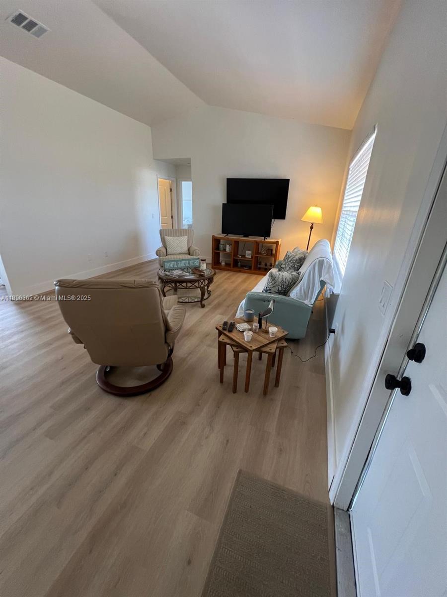 A living room features light wood-look flooring, a vaulted ceiling, and a light-colored sofa — 6191 Drucker circle, Port Charlotte FL 33981, PORT CHARLOTTE, FL
