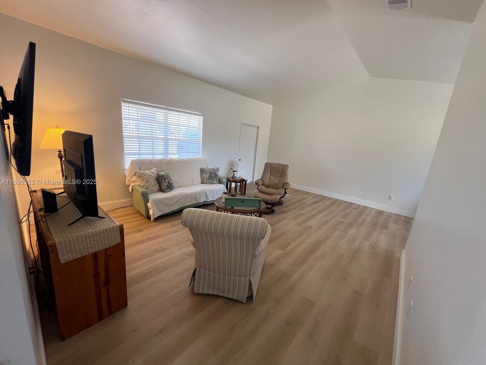 A living room features light wood-look flooring, white walls, a sofa, and two armchairs — 6191 Drucker circle, Port Charlotte FL 33981, PORT CHARLOTTE, FL