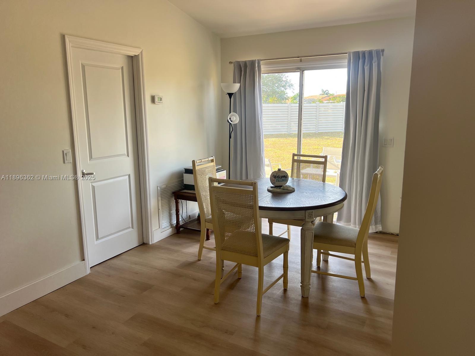 A dining area features a round wooden table, four chairs, and a sliding glass door — 6191 Drucker circle, Port Charlotte FL 33981, PORT CHARLOTTE, FL
