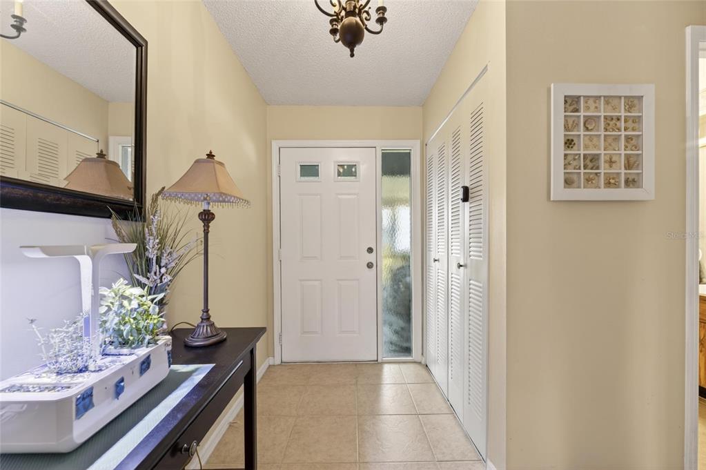 An entryway features a tiled floor, a white front door, and a console table — 1517 INGRAM DRIVE, SUN CITY CENTER, FL