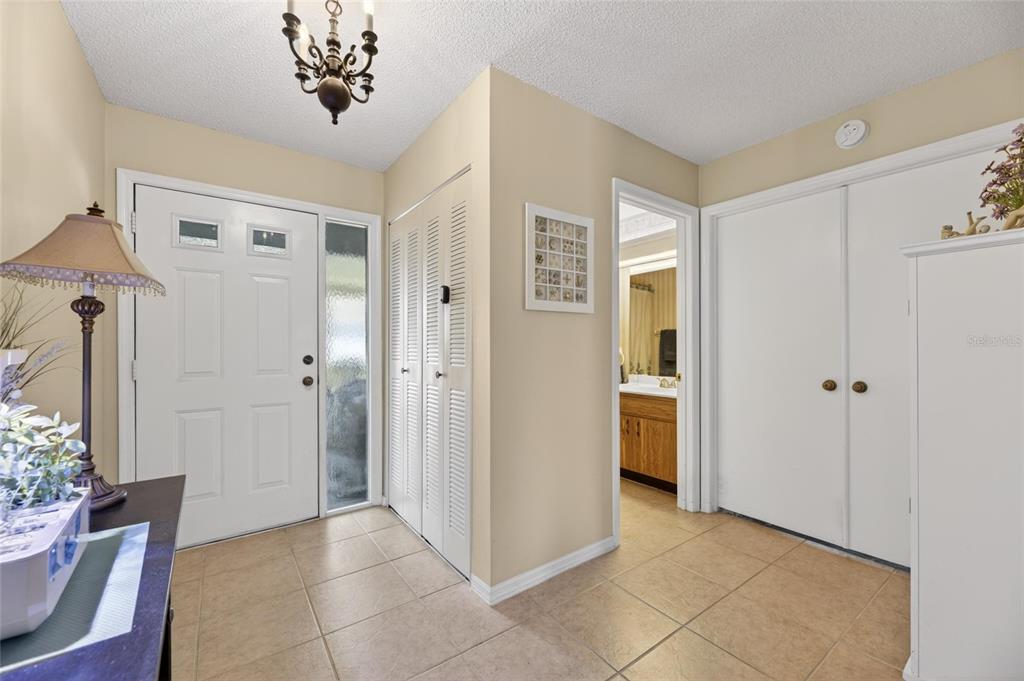 An entryway features a white front door, tiled floors, a chandelier, and two closet doors — 1517 INGRAM DRIVE, SUN CITY CENTER, FL