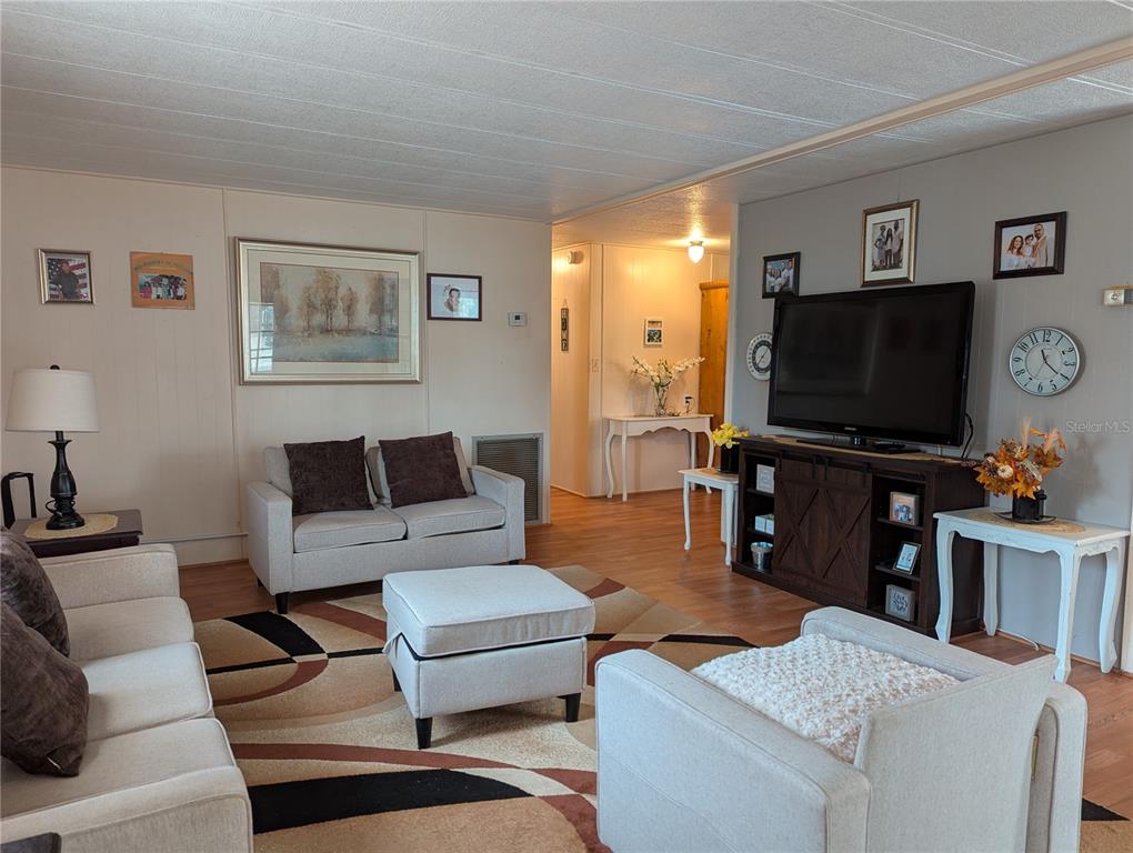 A living room features light-colored sofas, a patterned area rug, and a television on a stand — 1610 REYNOLDS ROAD UNIT 154, LAKELAND, FL