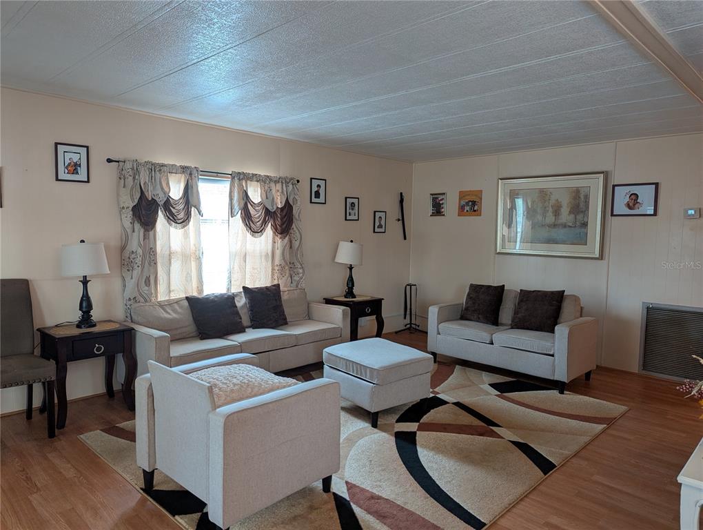 A living room features light-colored furniture, a patterned area rug, and wood-look flooring — 1610 REYNOLDS ROAD UNIT 154, LAKELAND, FL