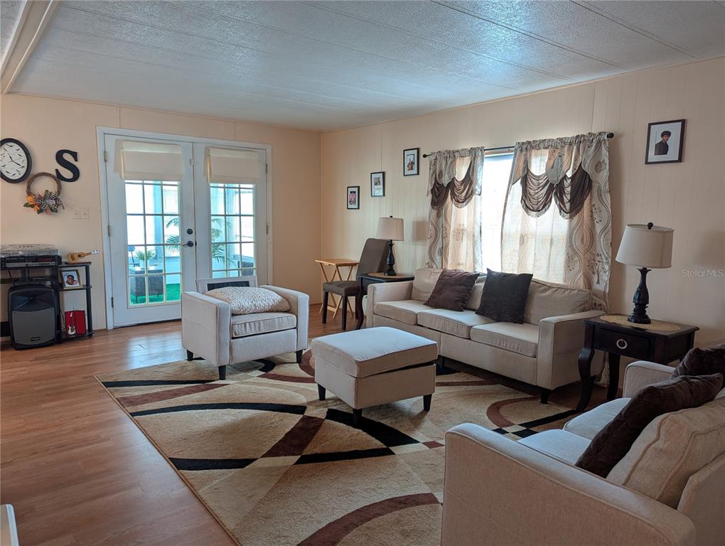 A living room features light-colored furniture, a patterned area rug, and French doors — 1610 REYNOLDS ROAD UNIT 154, LAKELAND, FL