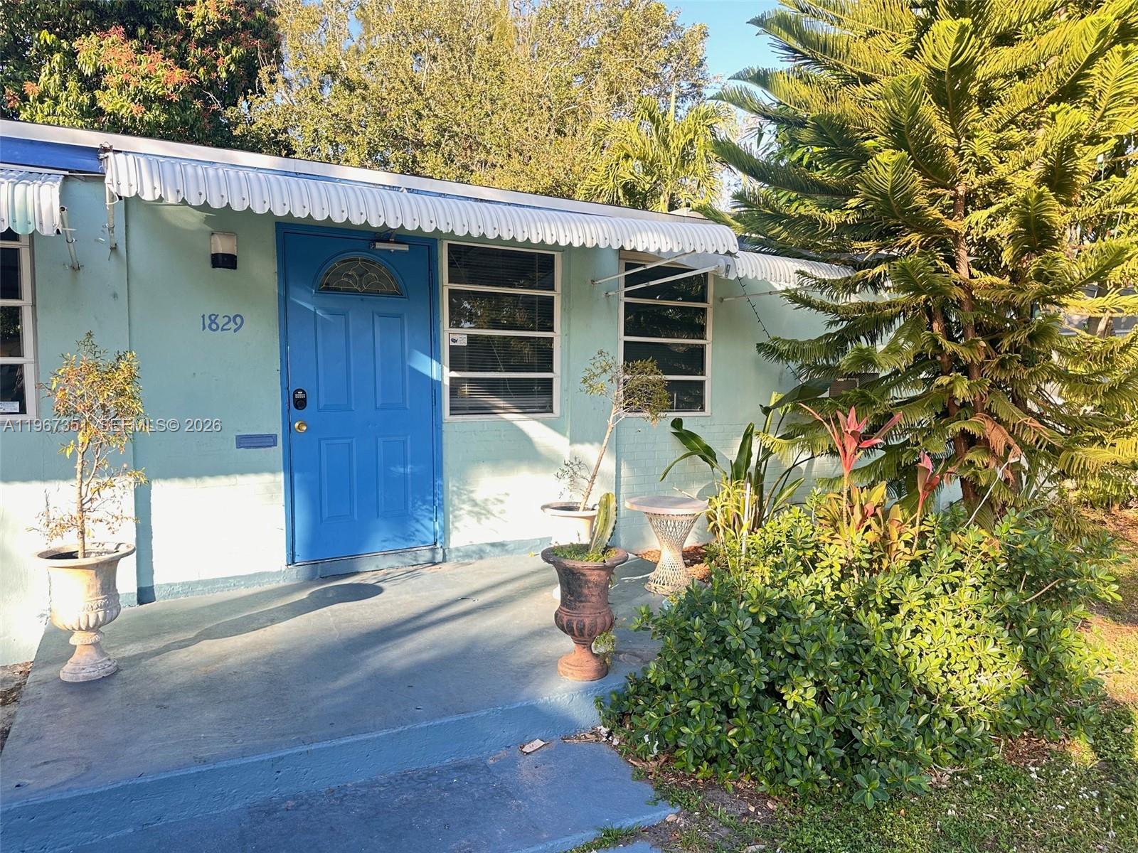 A light blue house exterior features a bright blue front door and a covered porch — 1829 Harding St, Hollywood FL 33020, HOLLYWOOD, FL