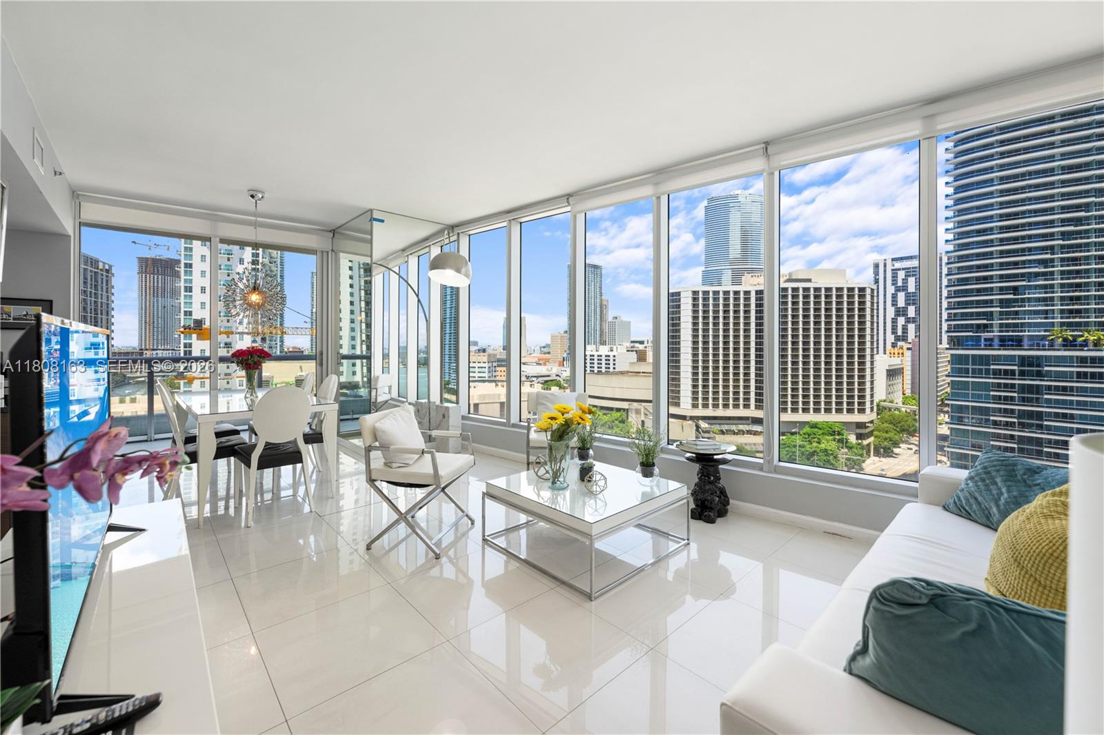 A modern living and dining area features floor-to-ceiling windows with expansive city skyline views — 485 Brickell Ave # 1604, Miami FL 33131, MIAMI, FL