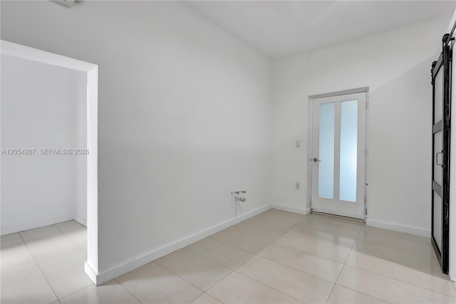 This laundry room features white walls, light tile flooring, and a sliding barn door — 7000 NW 2 Ave # 7000, Miami FL 33150, MIAMI, FL