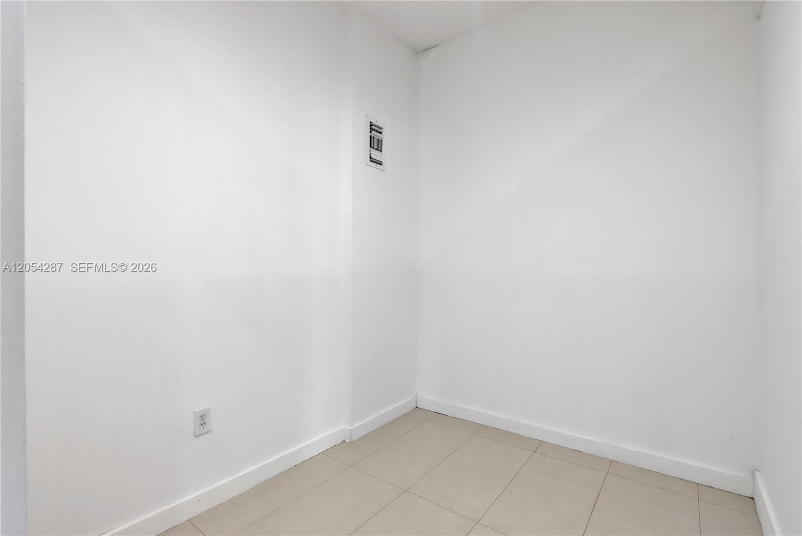 An empty corner room features white walls, light-colored tile flooring, and a wall outlet — 7000 NW 2 Ave # 7000, Miami FL 33150, MIAMI, FL