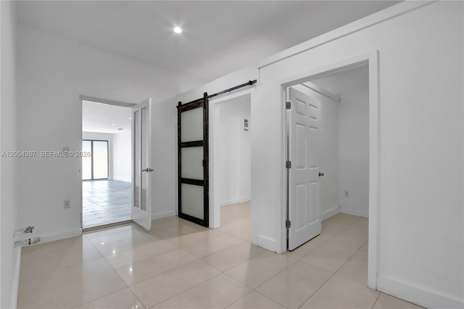 A room with tiled floors features a glass-paneled door, a sliding barn door, and a doorway — 7000 NW 2 Ave # 7000, Miami FL 33150, MIAMI, FL