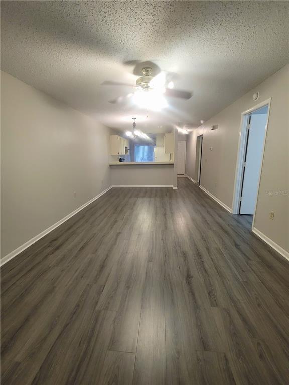 A long living room with gray wood-look flooring, light gray walls, and a ceiling fan — 410 LANDING BOULEVARD UNIT 1, INVERNESS, FL