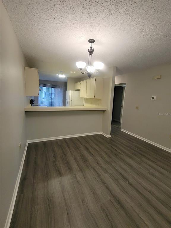 A dining area with wood-look flooring opens to a kitchen featuring white cabinets and counters — 410 LANDING BOULEVARD UNIT 1, INVERNESS, FL