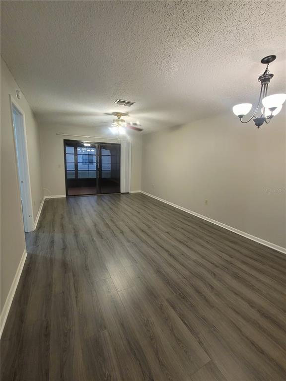 An empty living room features gray wood-look flooring, a ceiling fan, and sliding glass doors — 410 LANDING BOULEVARD UNIT 1, INVERNESS, FL