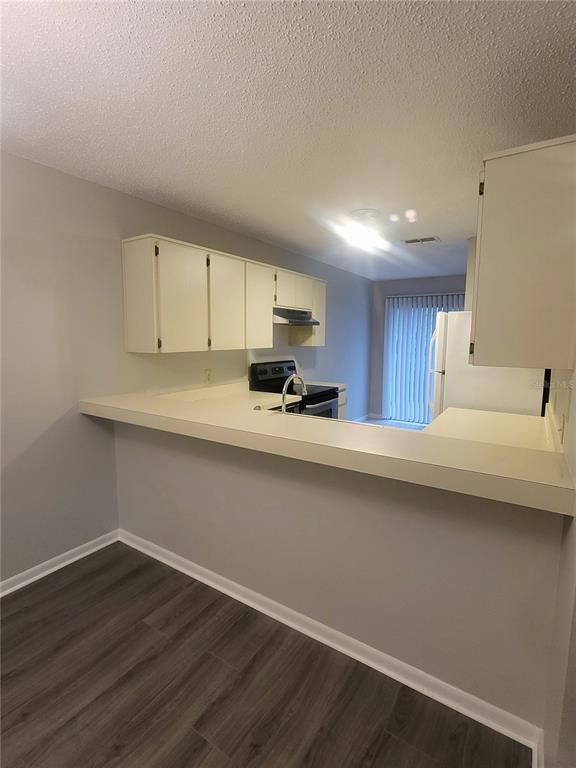 A kitchen with white cabinets, a breakfast bar, and dark wood-look flooring — 410 LANDING BOULEVARD UNIT 1, INVERNESS, FL