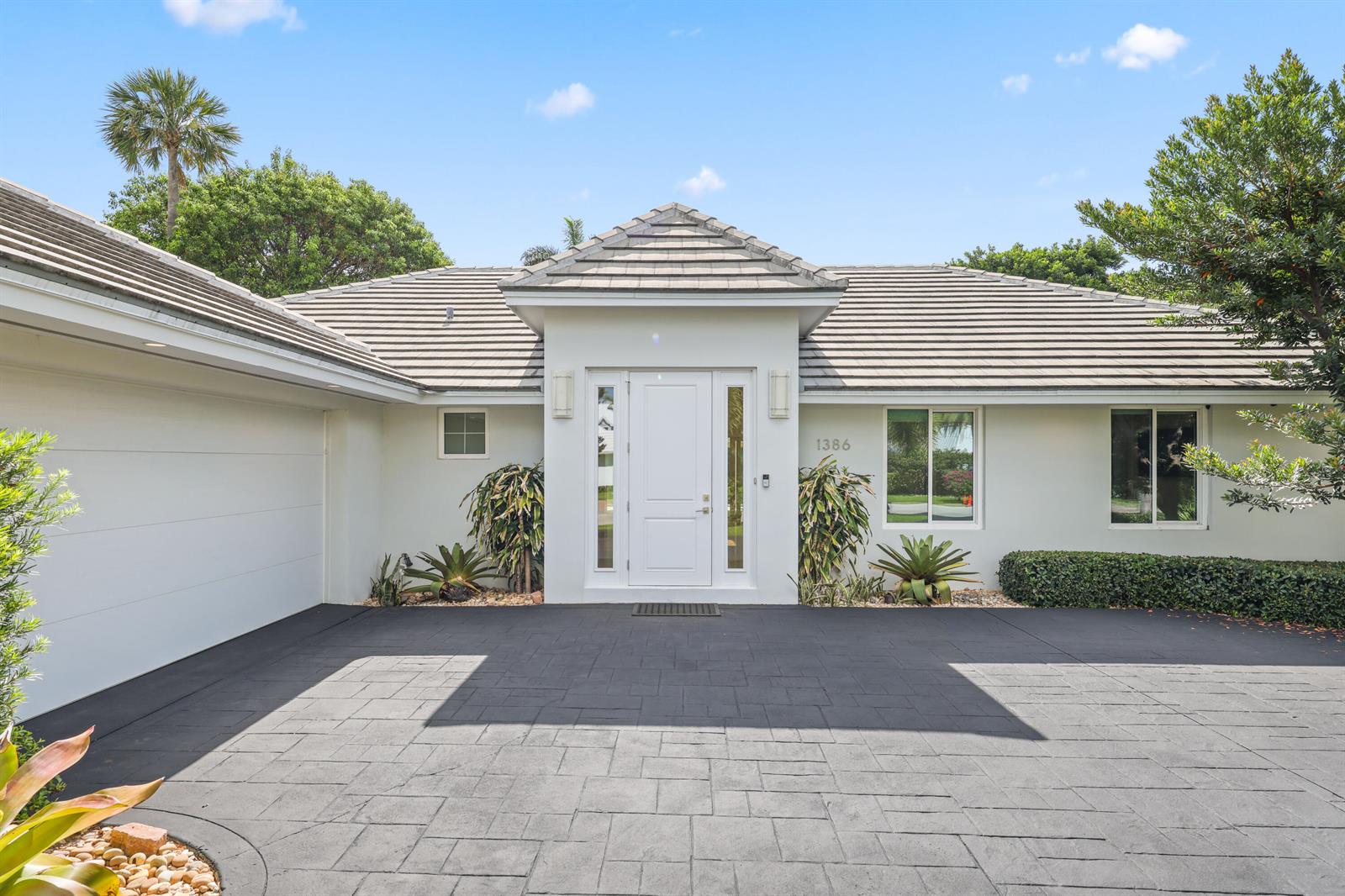The exterior view shows a white house with a gray tiled roof and paved driveway — 1386 S Atlantic Drive, Lantana FL 33462, LANTANA, FL