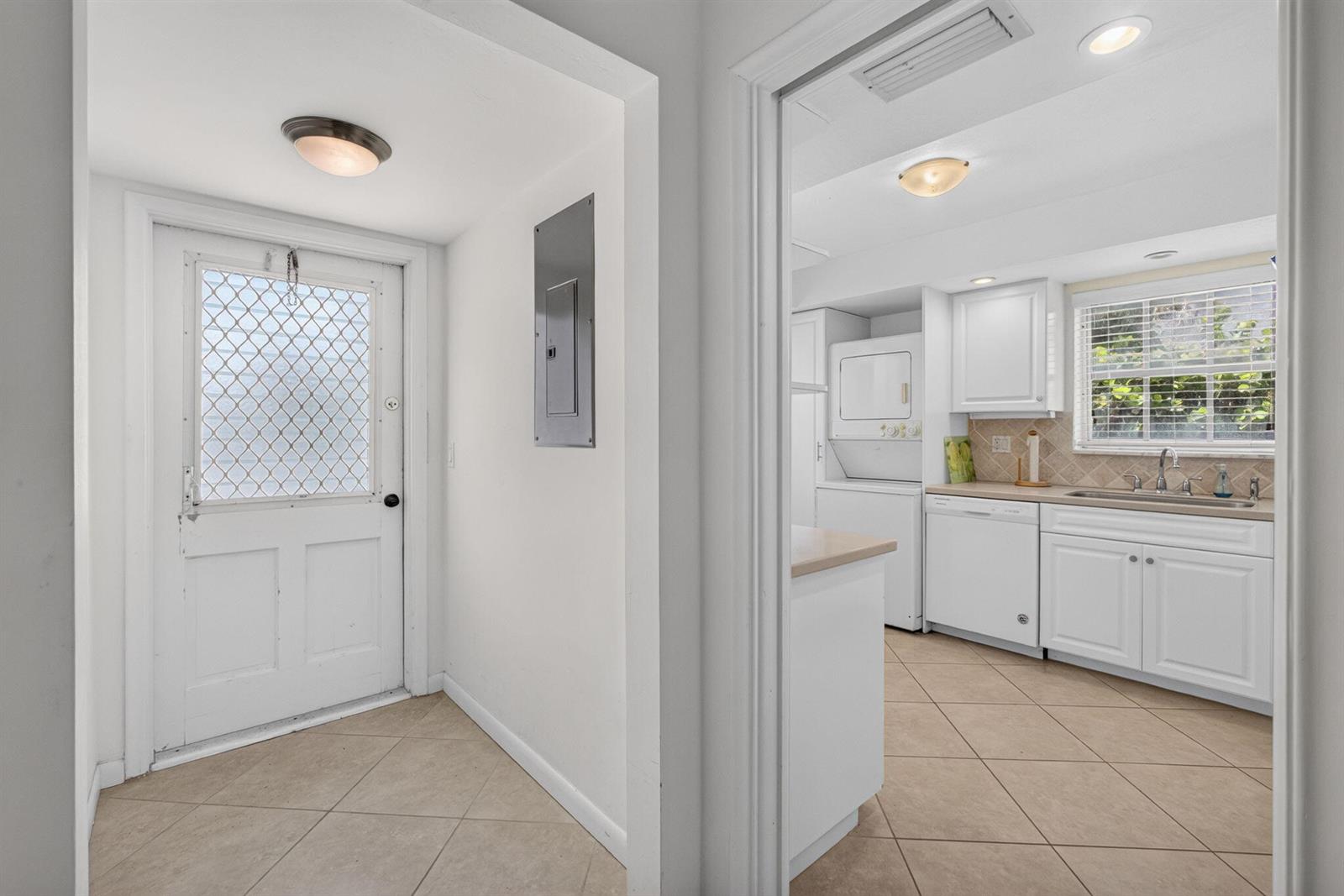 An entryway with a white door leads to a kitchen featuring white cabinets and appliances — 120 Celestial Way # 114, Juno Beach FL 33408, JUNO BEACH, FL