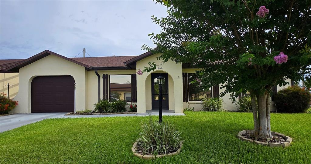 A single-story house with a garage, a front entrance, and a large tree in front — 1980 TRINITY CIRCLE, HAINES CITY, FL