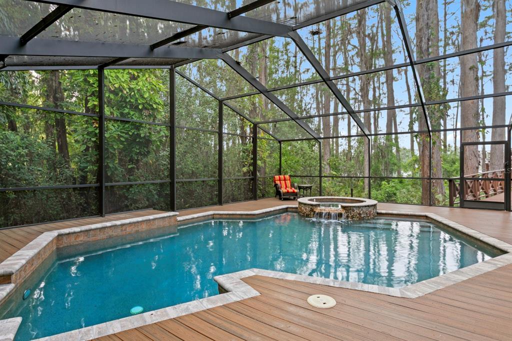 A screened-in pool and hot tub with a waterfall feature on a wooden deck — 8817 ROBERTS ROAD, ODESSA, FL