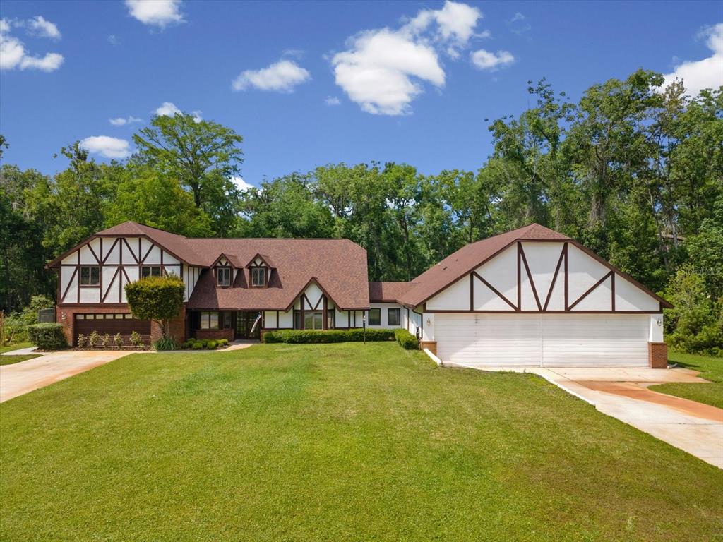 A two-story Tudor-style house with a large lawn and an attached multi-car garage — 10721 SKYHAWK DRIVE, NEW PORT RICHEY, FL