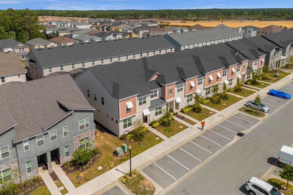 An aerial view shows a row of multi-story townhouses with parking spaces in front — 1644 TROPICAL PALMS CIRCLE, KISSIMMEE, FL