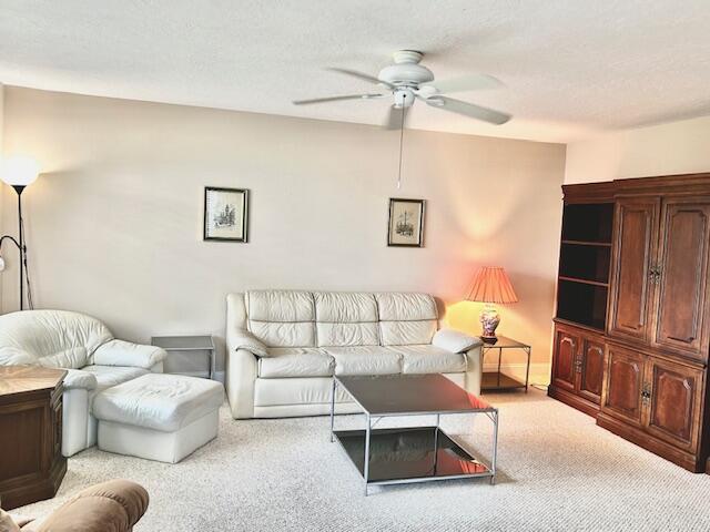 A living room features a white leather sofa, matching armchair with ottoman, and wooden cabinetry — 715 Normandy O, Delray Beach FL 33484, DELRAY BEACH, FL
