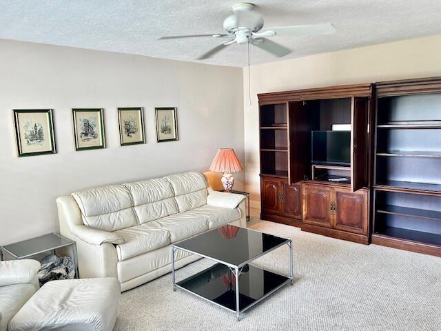 A living room features a white leather sofa, a glass coffee table, and wooden cabinetry — 715 Normandy O, Delray Beach FL 33484, DELRAY BEACH, FL