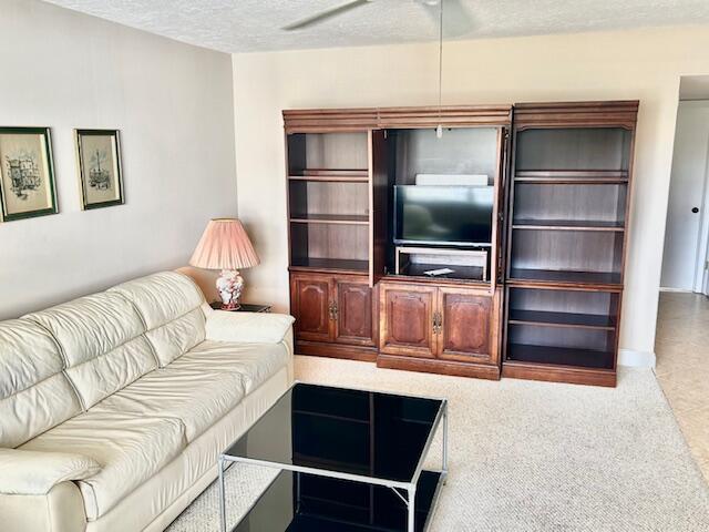 A living room features a white leather sofa, a glass coffee table, and wooden shelving — 715 Normandy O, Delray Beach FL 33484, DELRAY BEACH, FL
