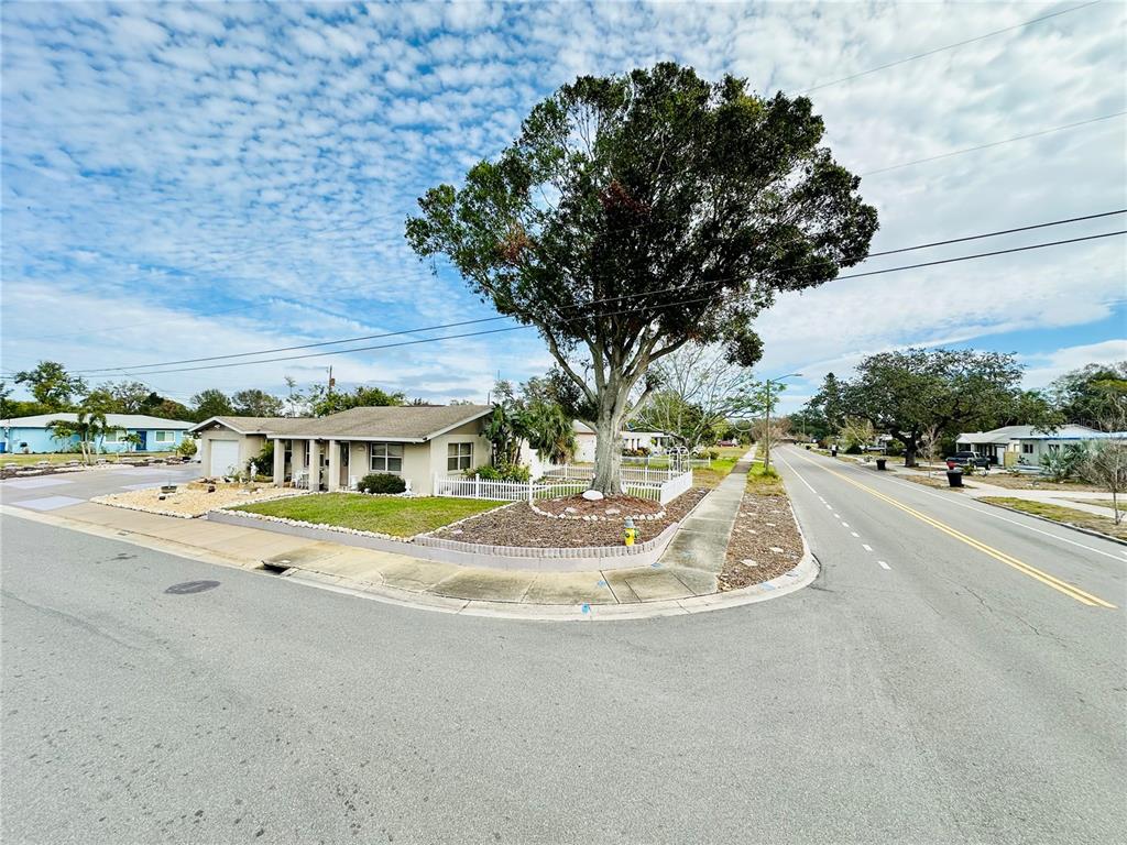 A single-story house with a large tree in the front yard sits on a corner lot — 6190 6TH STREET S, ST PETERSBURG, FL