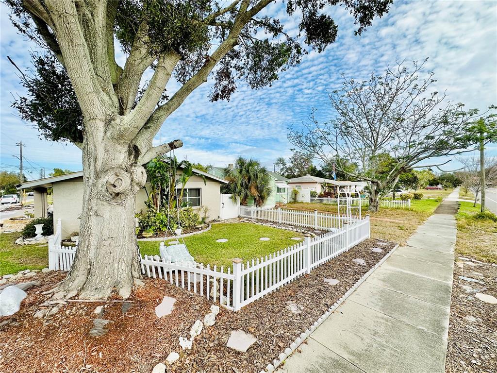A white picket fence encloses a front yard with a large tree and a swing — 6190 6TH STREET S, ST PETERSBURG, FL