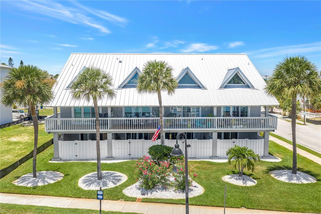A two-story house with a white metal roof, a wrap-around balcony, and palm trees — 1010 PASS A GRILLE WAY UNIT 2, ST PETE BEACH, FL