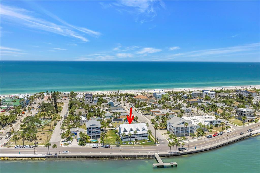 An aerial view shows a white multi-story building near a beach and a bay — 1010 PASS A GRILLE WAY UNIT 2, ST PETE BEACH, FL