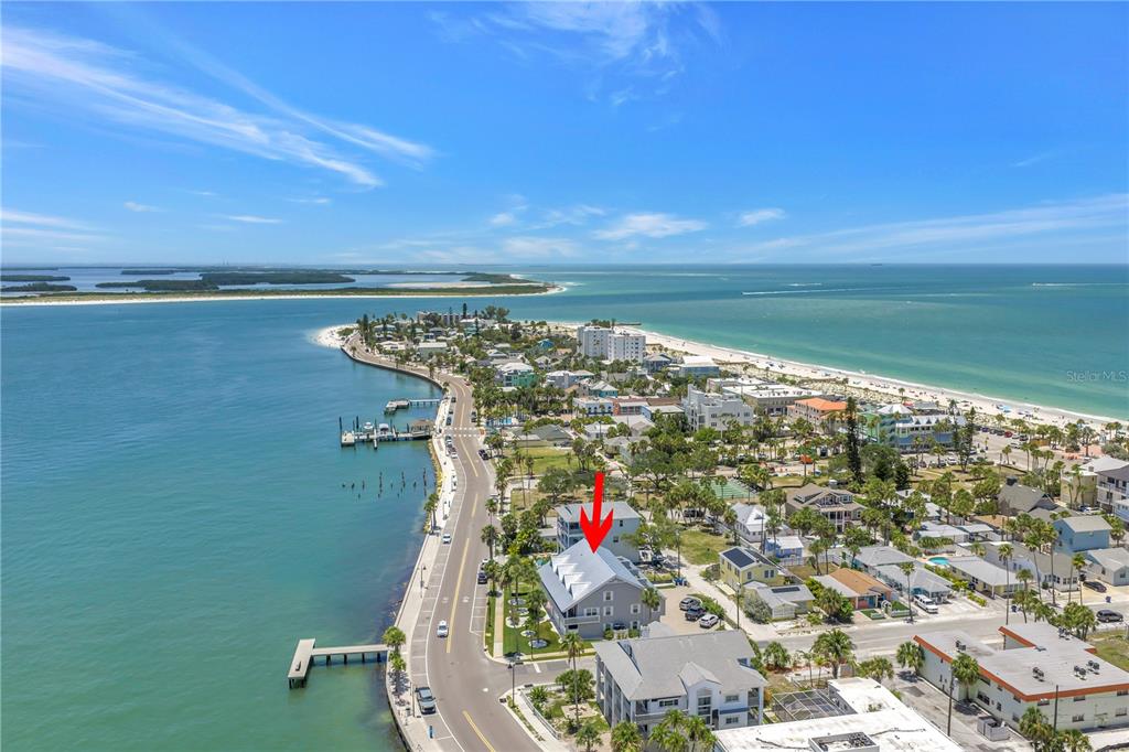 An aerial view shows a coastal neighborhood with a red arrow pointing to a building — 1010 PASS A GRILLE WAY UNIT 2, ST PETE BEACH, FL