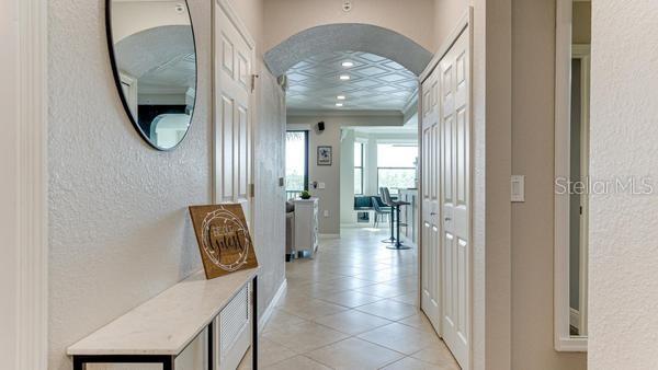 A hallway with a marble-topped console table leads to an arched entryway into a living area — 16706 VARDON TERRACE UNIT 303, BRADENTON, FL