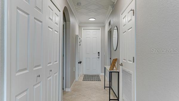 A hallway with tile floors, white paneled doors, and a decorative coffered ceiling — 16706 VARDON TERRACE UNIT 303, BRADENTON, FL