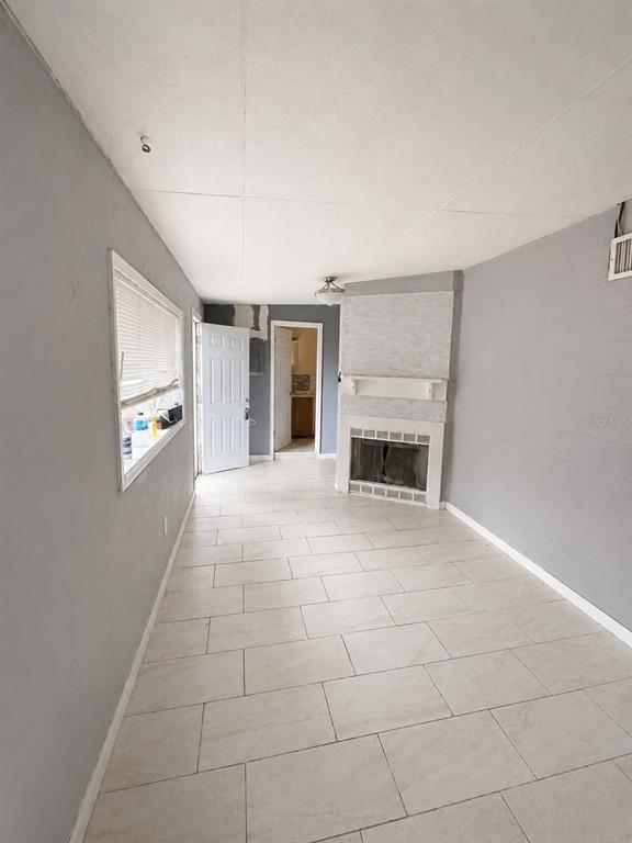 A living room with light-colored tile flooring, gray walls, and a white brick fireplace — 4615 CLARCONA OCOEE ROAD, ORLANDO, FL