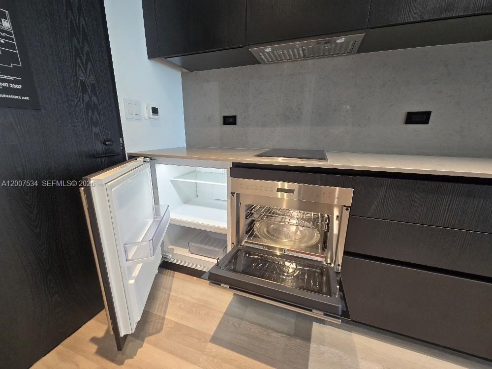 A modern kitchen features dark cabinetry, a built-in oven, and an under-counter refrigerator — 20 NE NE 11 Street # 2307, Miami FL 33132, MIAMI, FL