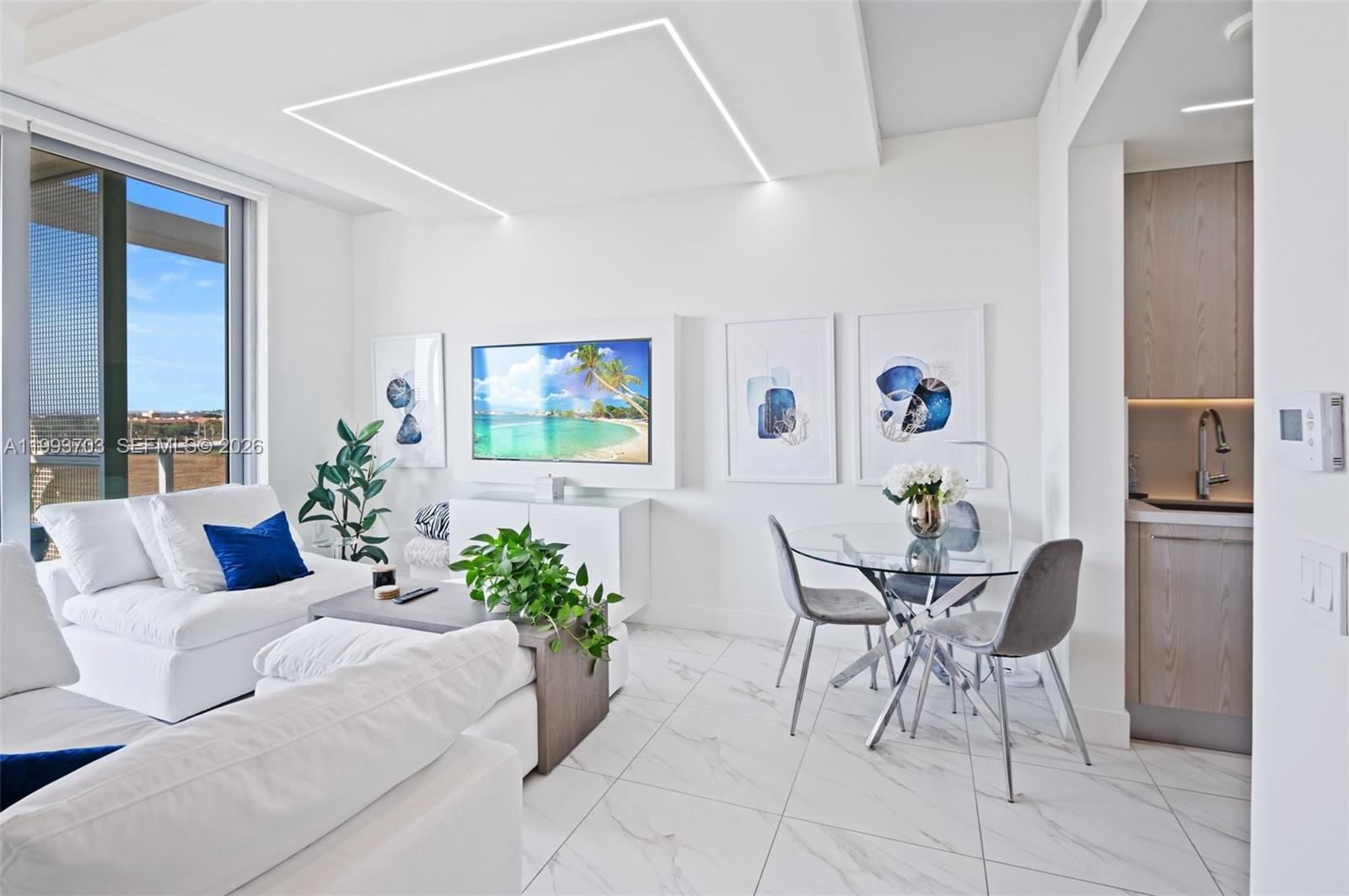 A modern living and dining area features white furniture, marble floors, and a balcony view — 2000 Metropica Way # 508, Sunrise FL 33323, SUNRISE, FL