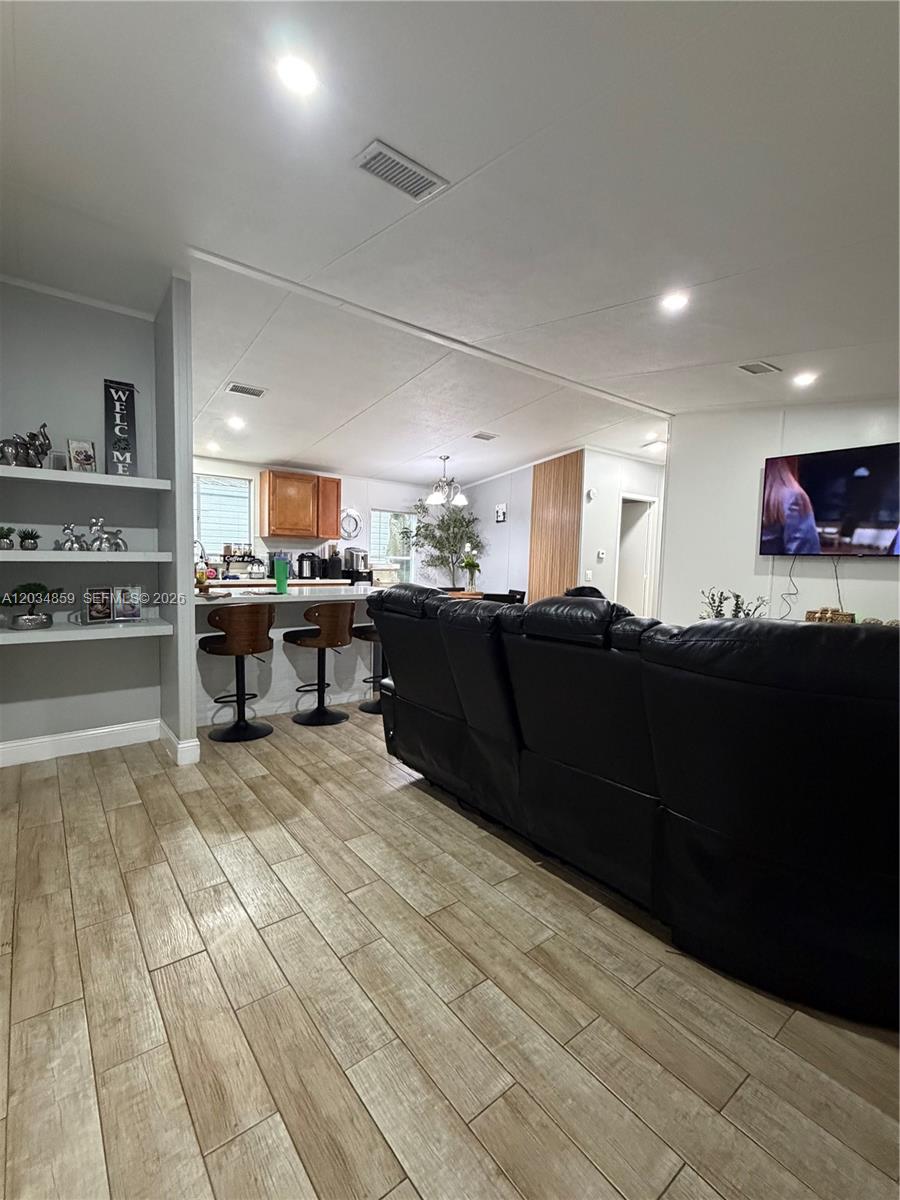 A living room with wood-look tile flooring opens into a kitchen with a breakfast bar — 19800 SW 180th Ave, Miami FL 33187, MIAMI, FL
