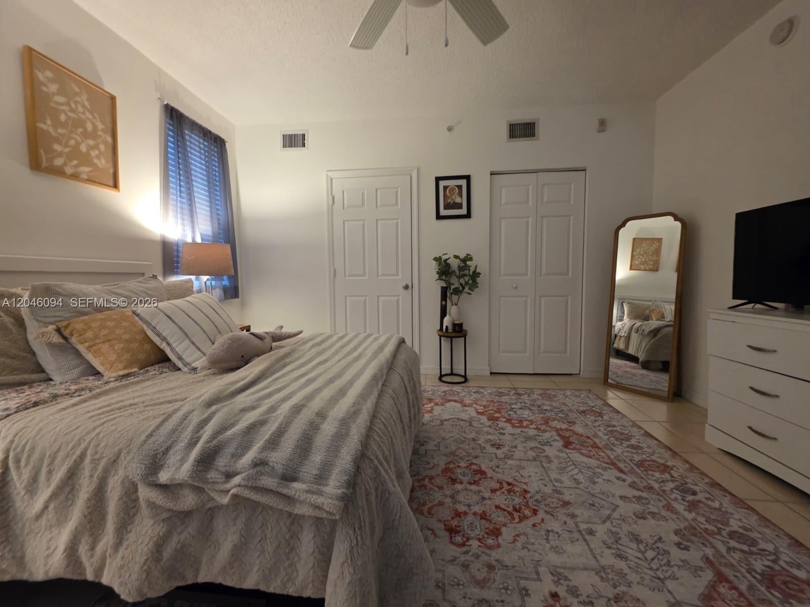A bedroom features a bed with patterned bedding, a rug, a mirror, and a dresser — 2201 W Preserve Way # 208, Miramar FL 33025, MIRAMAR, FL